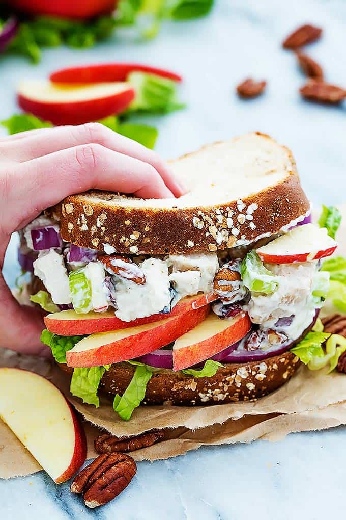 a hand picking up a apple pecan chicken salad sandwich.