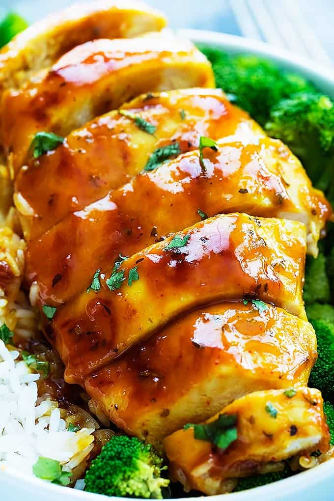 close up of baked honey mustard chicken with broccoli and rice in a bowl.