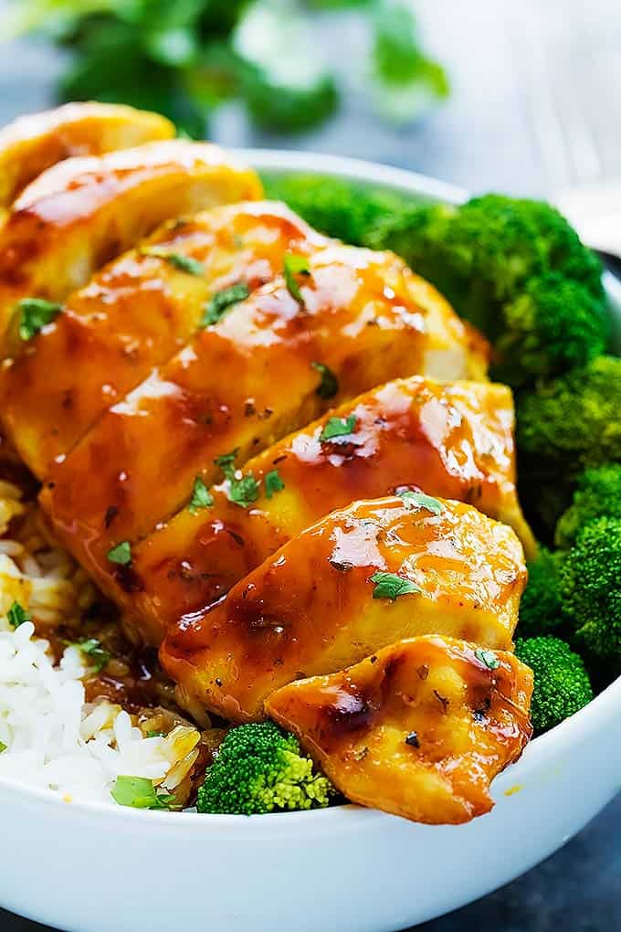 close up of baked honey mustard chicken with broccoli and rice in a bowl.