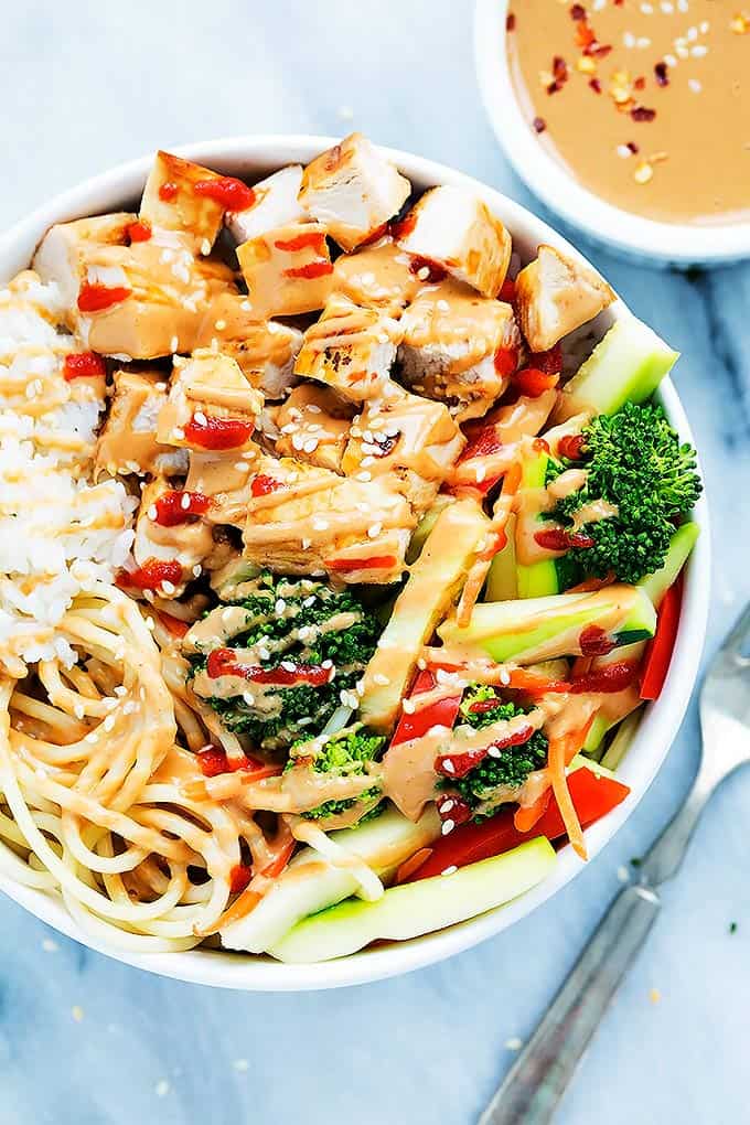 top view of a Bali Island chicken rice bowl with a fork and bowl of sauce on the side.