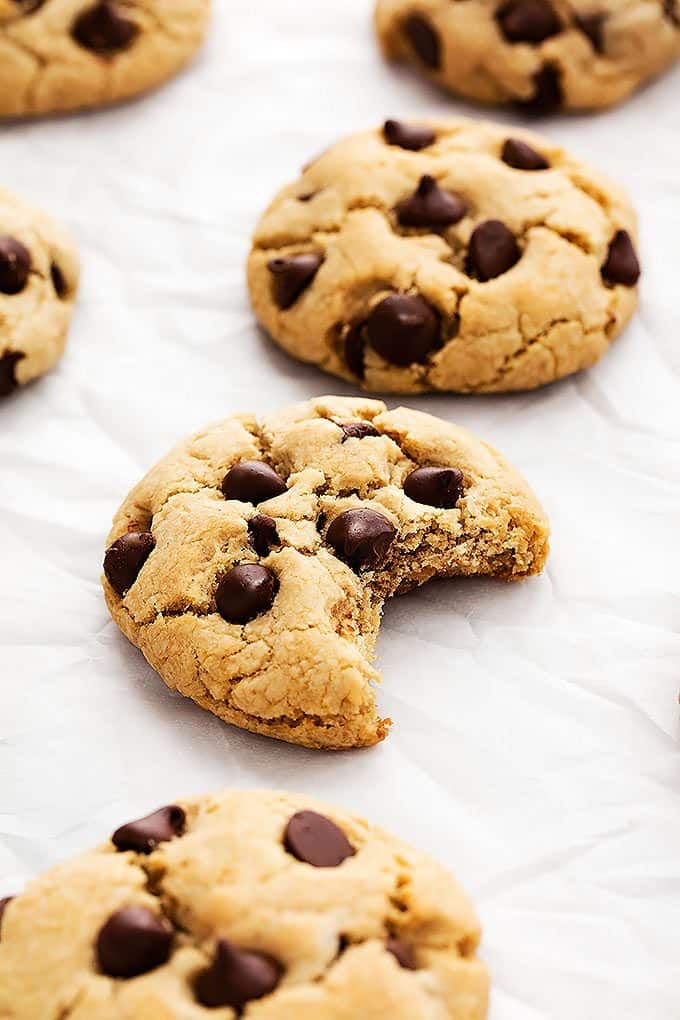 a coconut oil cream cheese chocolate chip cookie with a bite missing with more cookies around it.