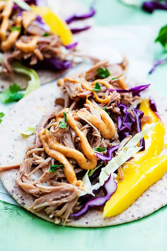 close up of an open kalua pork taco with another taco in the background.