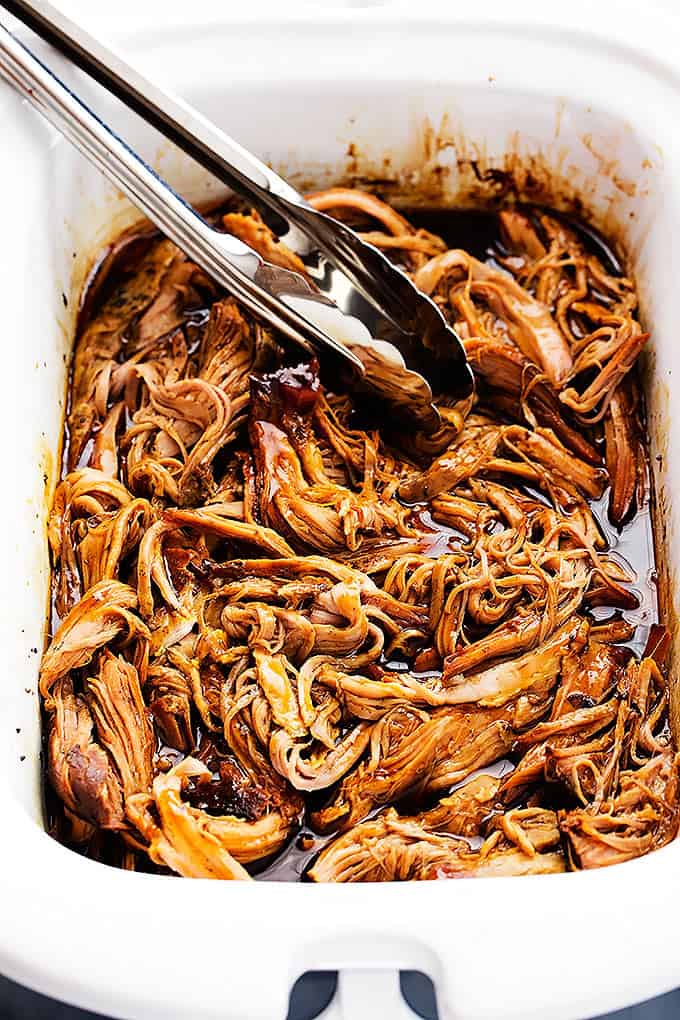 slow cooker honey balsamic pork tenderloin and tongs in a baking pan.