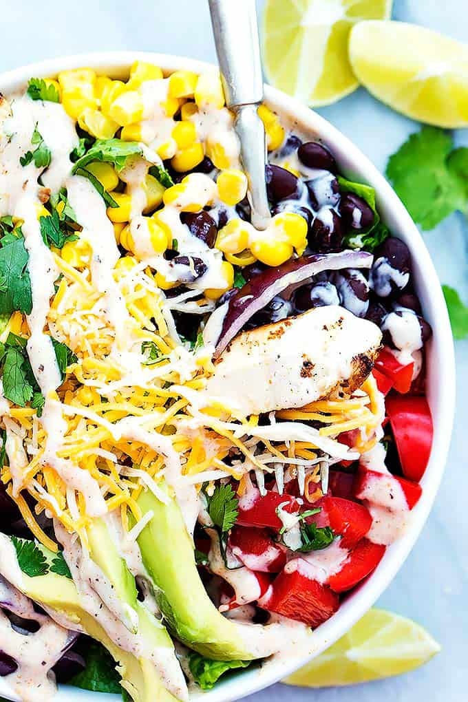 top view of Southwest chicken salad with a fork in a bowl with lime slices on the side.