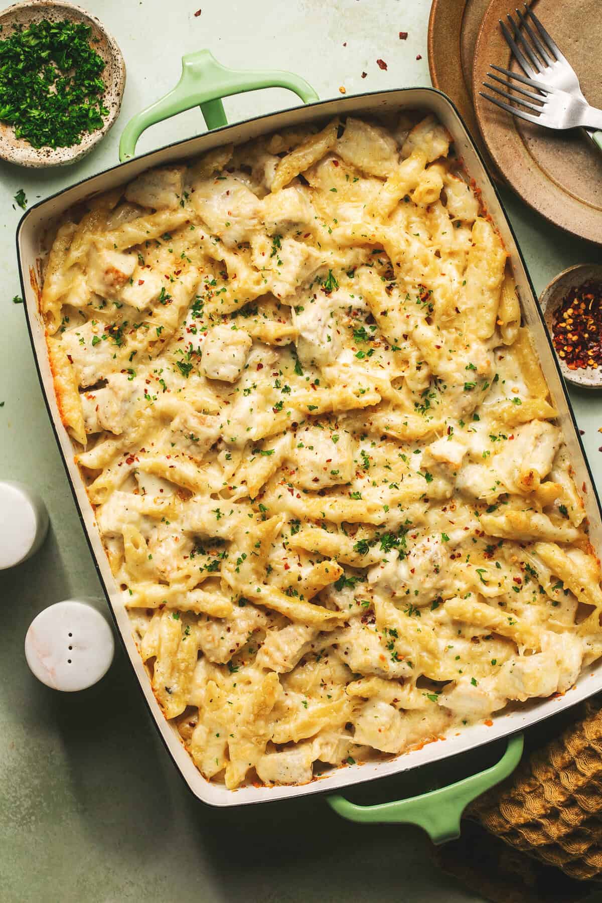 chicken and penne pasta in alfredo sauce topped with melted cheese in casserole dish on table