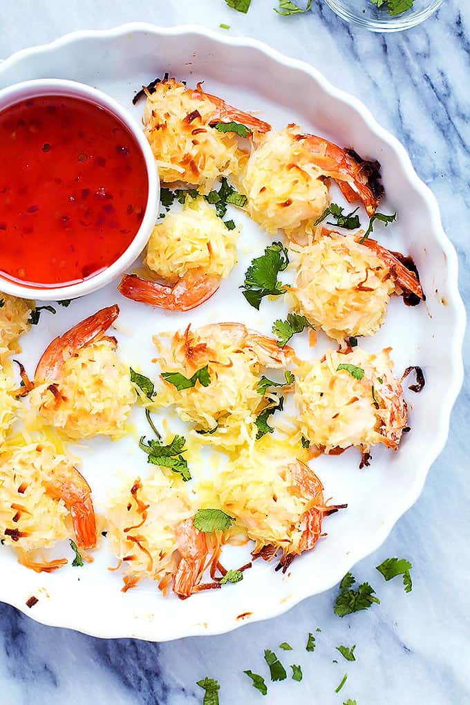 top view of baked coconut shrimp and a bowl of sweet and sour sauce on a plate.