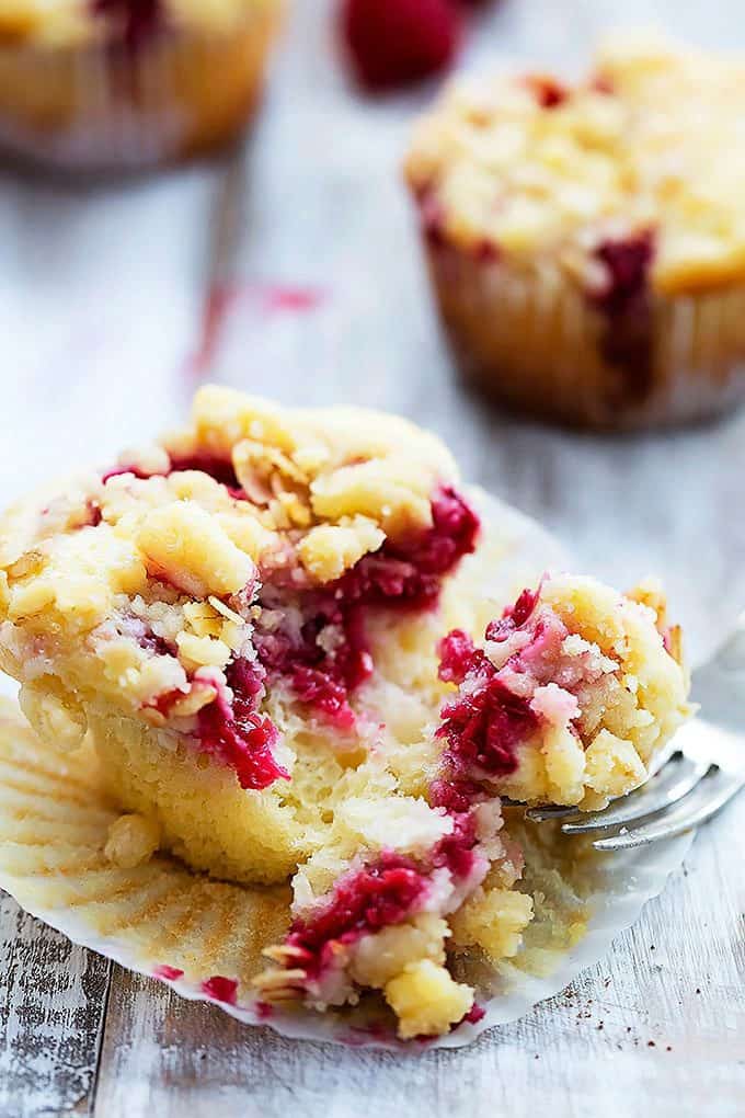 a raspberry crumb muffin with some bites on the side with a fork.
