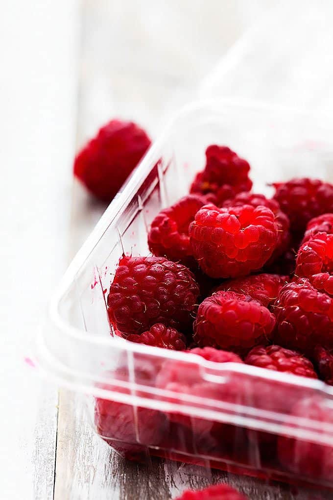 close up of raspberries in a plastic container.