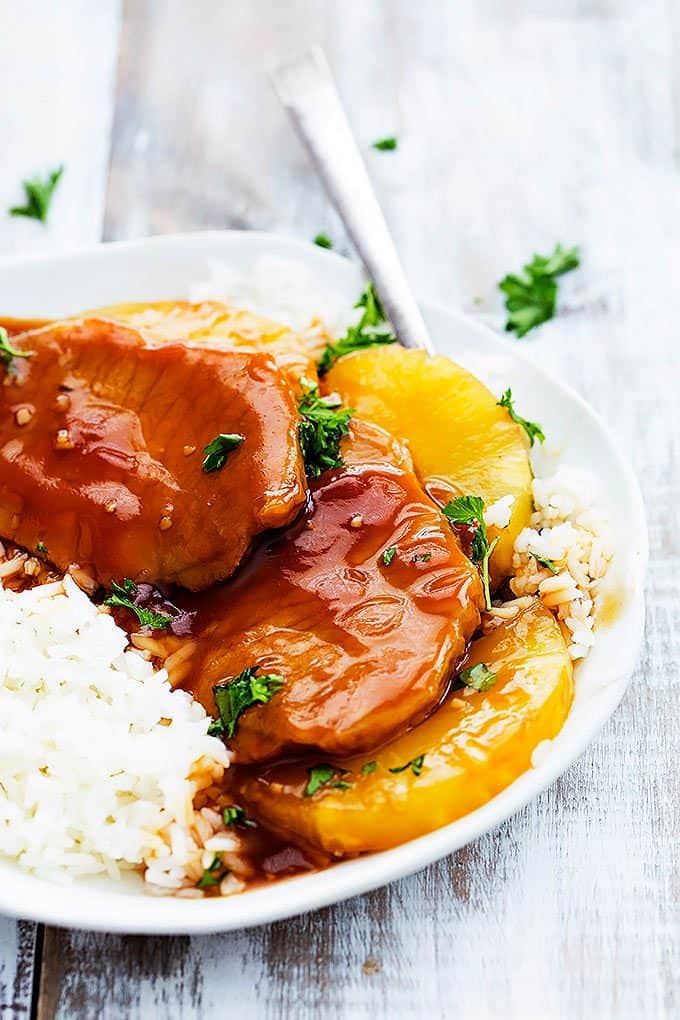 slow cooker Hawaiian pork chops on a rice with a fork on a plate.