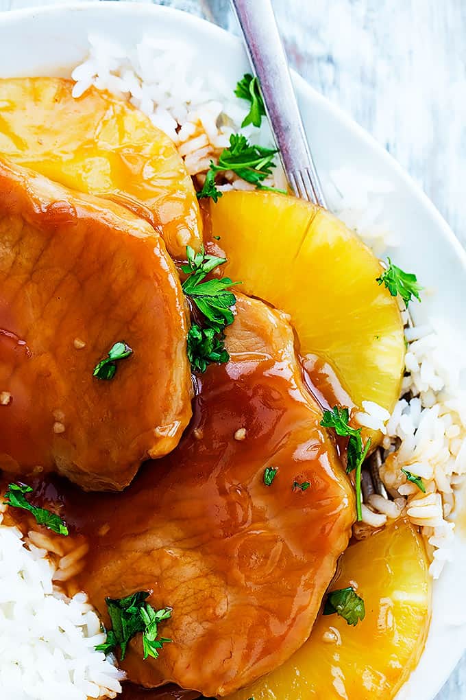 close up top view of slow cooker Hawaiian pork chops on rice with a fork on a plate.