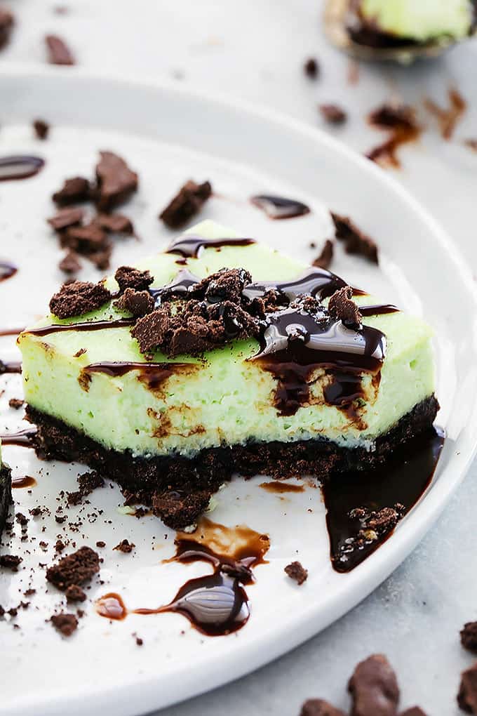 close up of a thin mint cheesecake bar with a bite missing on a plate.
