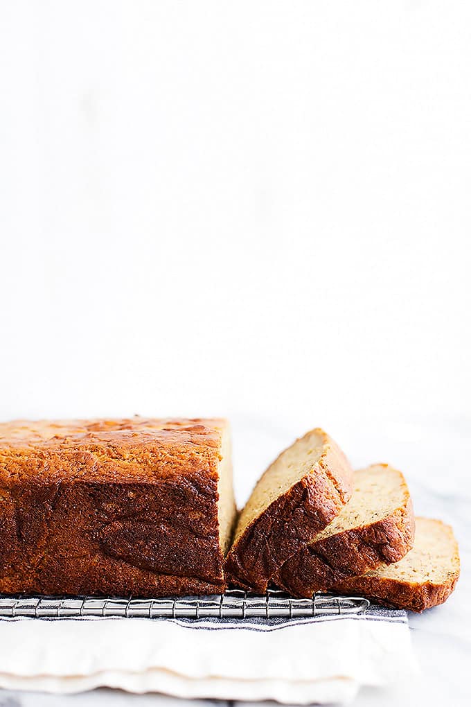 a loaf of brown butter banana bread with the front cut into slices on a cooling rack.