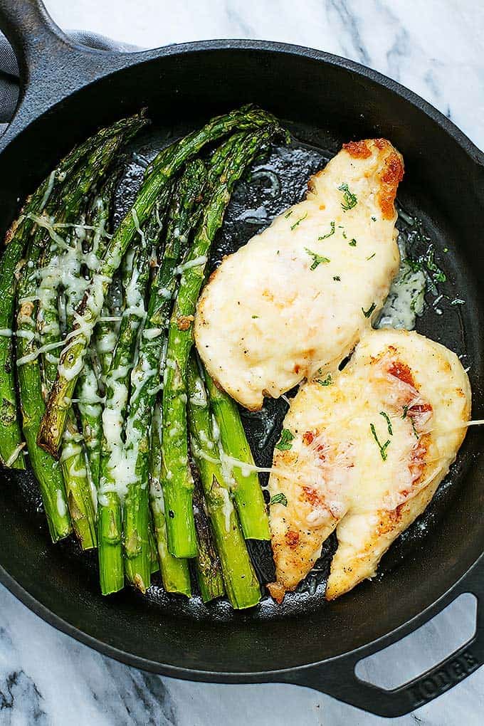 top view of garlic parmesan chicken & asparagus in a cast iron skillet.
