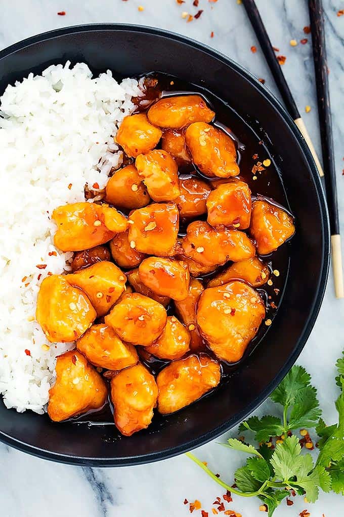 top view of slow cooker firecracker chicken with rice in a bowl with chopsticks on the side.