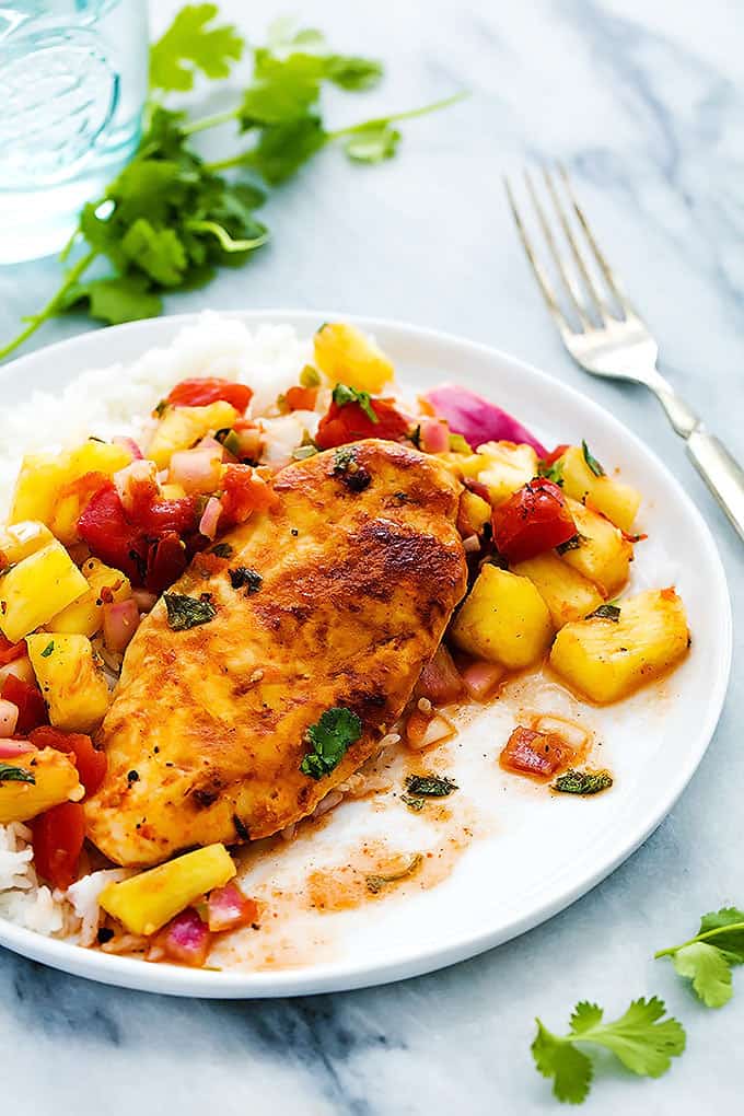 slow cooker pineapple salsa chicken with rice on a plate with a fork on the side.