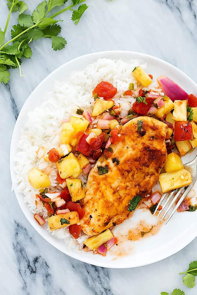 top view of slow cooker pineapple salsa chicken with rice and a fork on a plate.