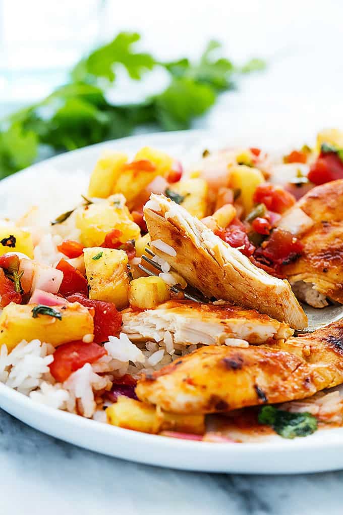 close up of slow cooker pineapple salsa chicken cut up with rice on a plate.