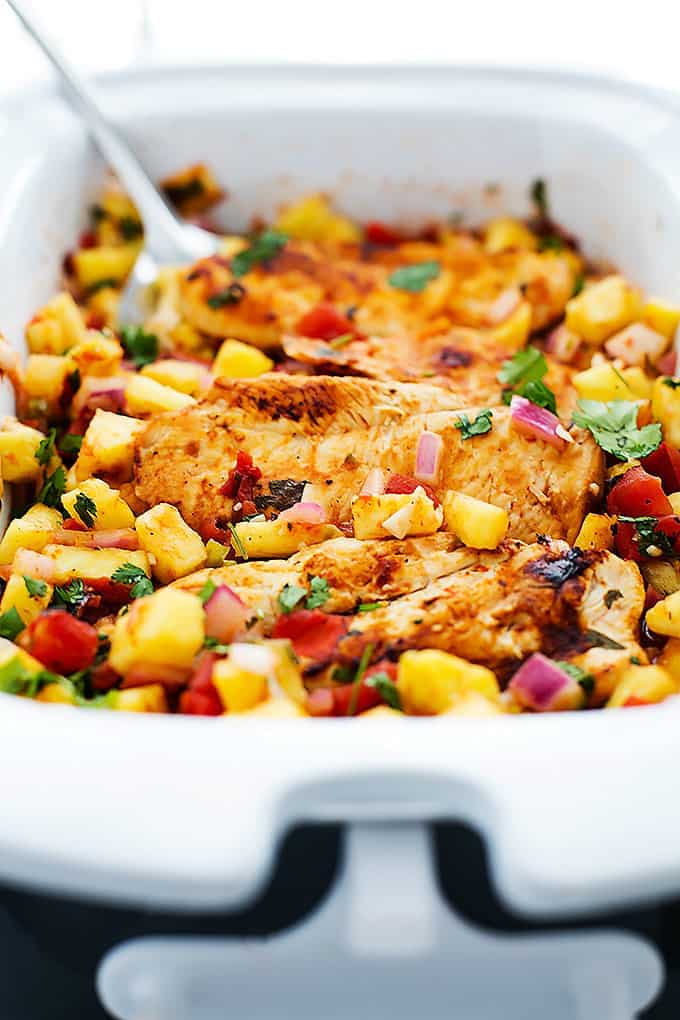 slow cooker pineapple salsa chicken with a spatula in a serving pan.