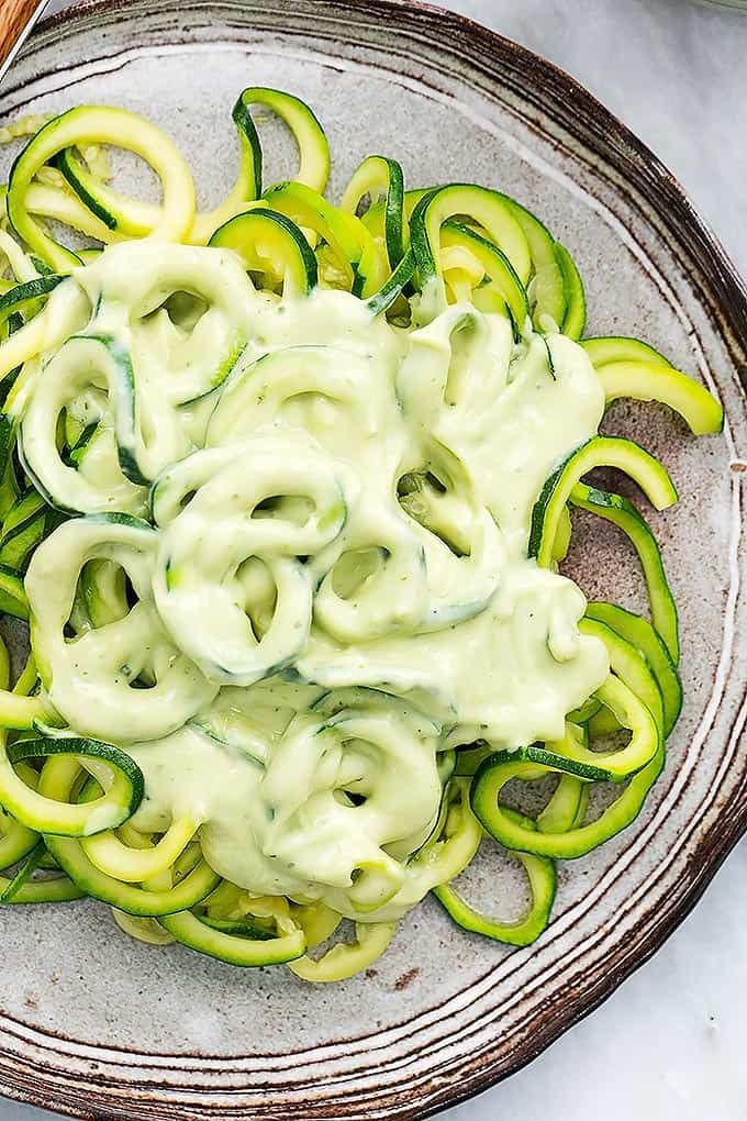 top view of zoodles (zucchini noodles) with cilantro lime avocado sauce on a plate.