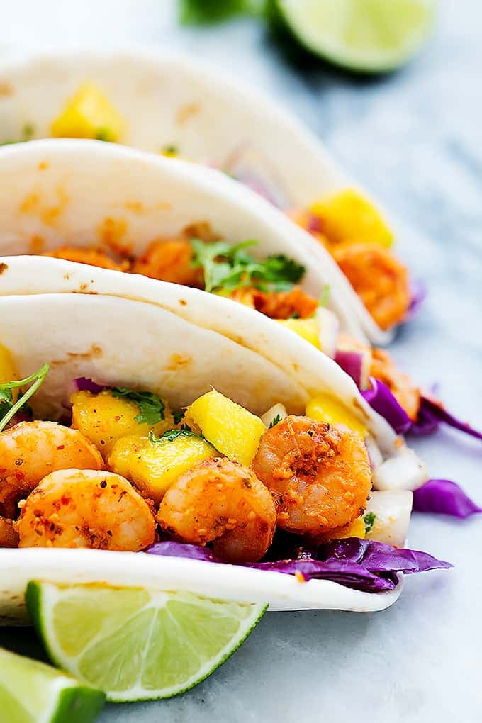 close up of Cajun shrimp tacos with mango salsa with lime slices on the side.