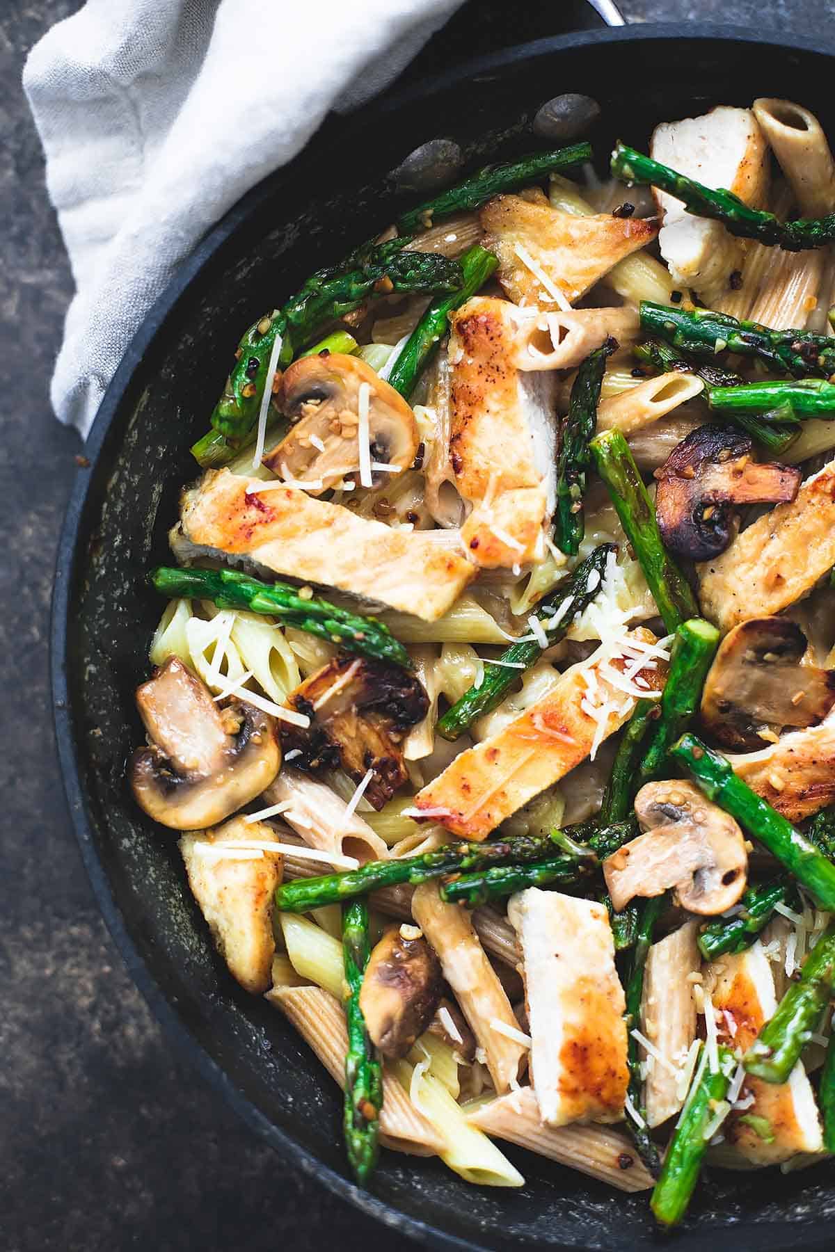 close up top view of garlic chicken mushroom and asparagus penne in a skillet.