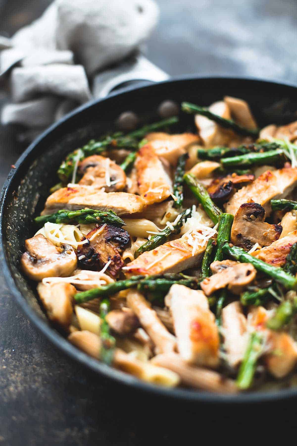 garlic chicken mushroom and asparagus penne in a skillet.