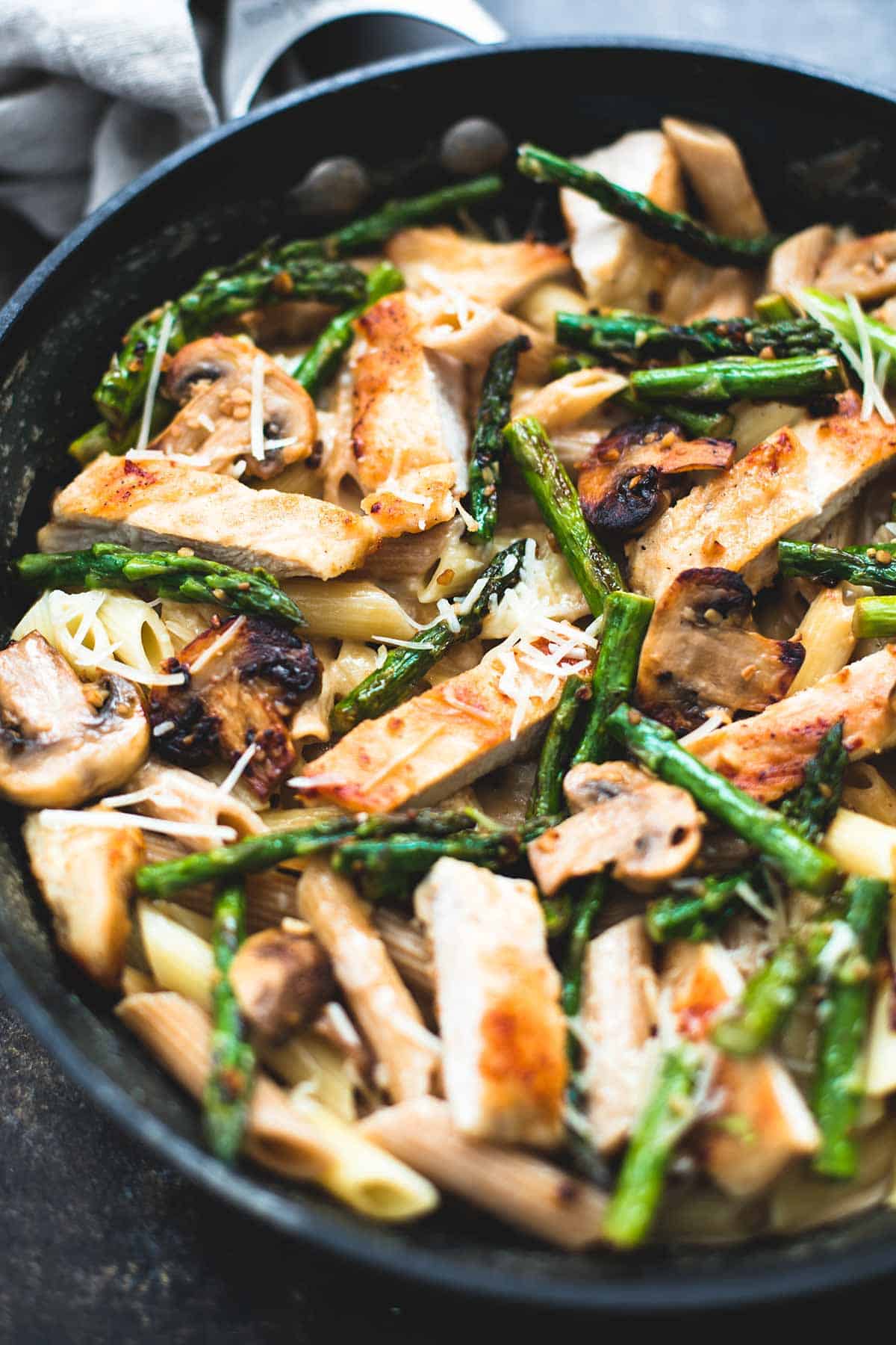 close up of garlic chicken mushroom and asparagus penne in a skillet.
