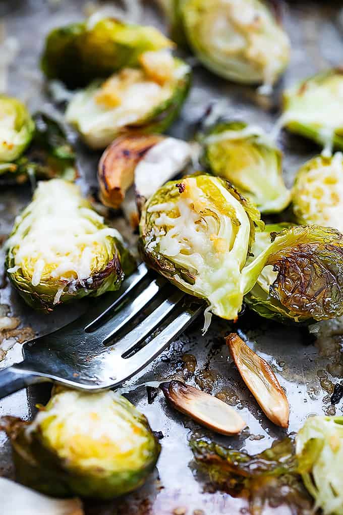 a roasted garlic parmesan brussel sprout on a fork with more brussel sprouts around it.