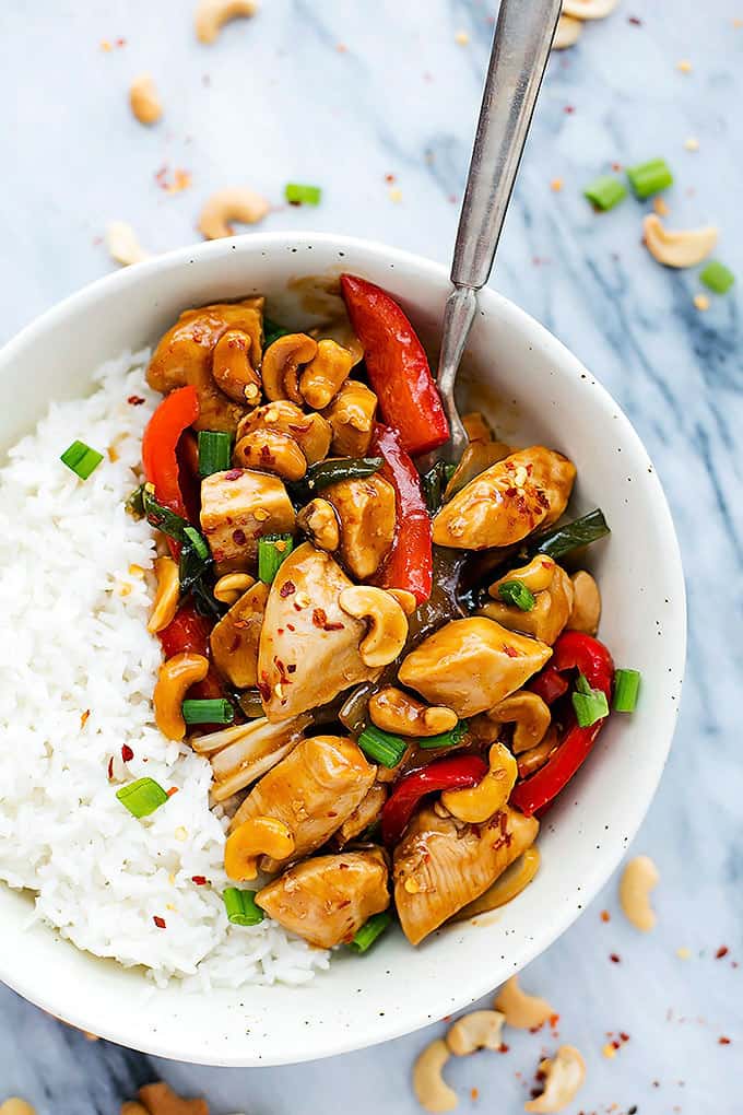 top view of slow cooker spicy cashew chicken with rice and a fork in a bowl.