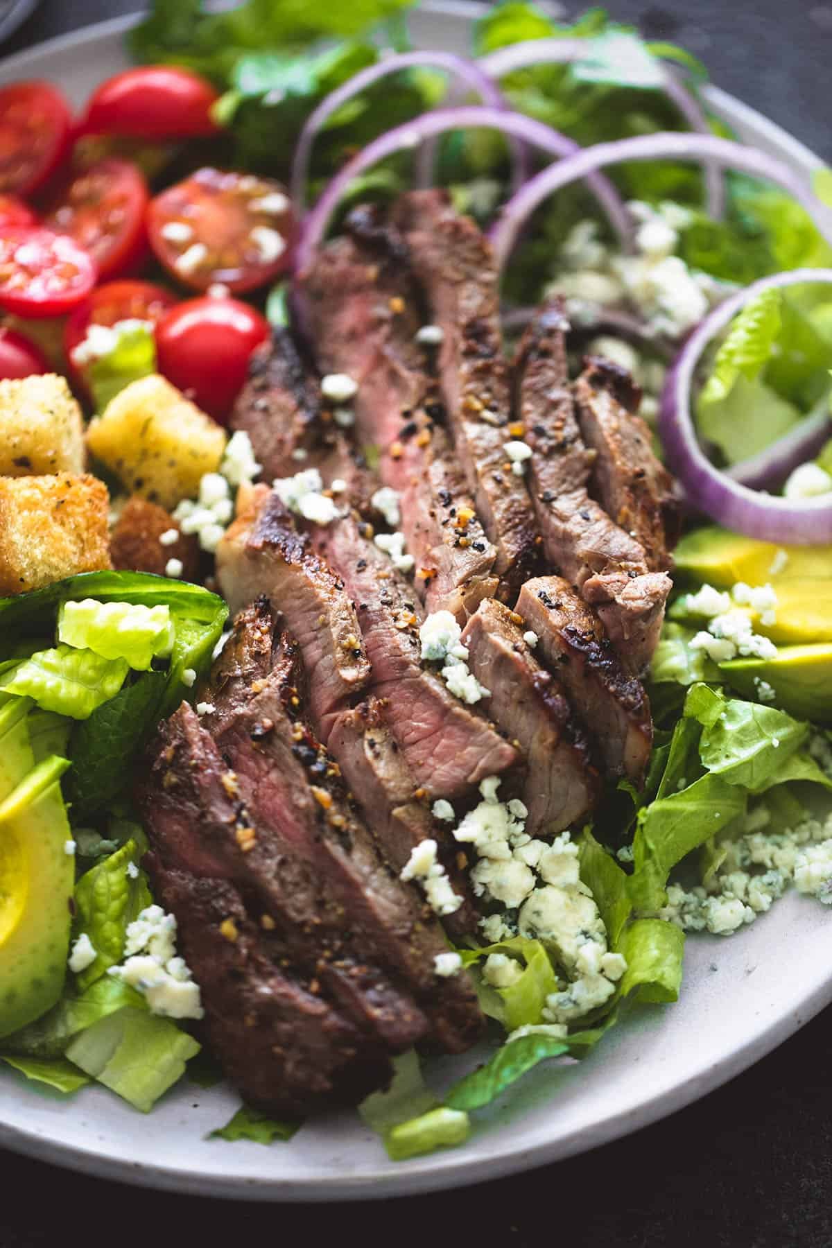 close up of black n' blue grilled steak salad on a plate.