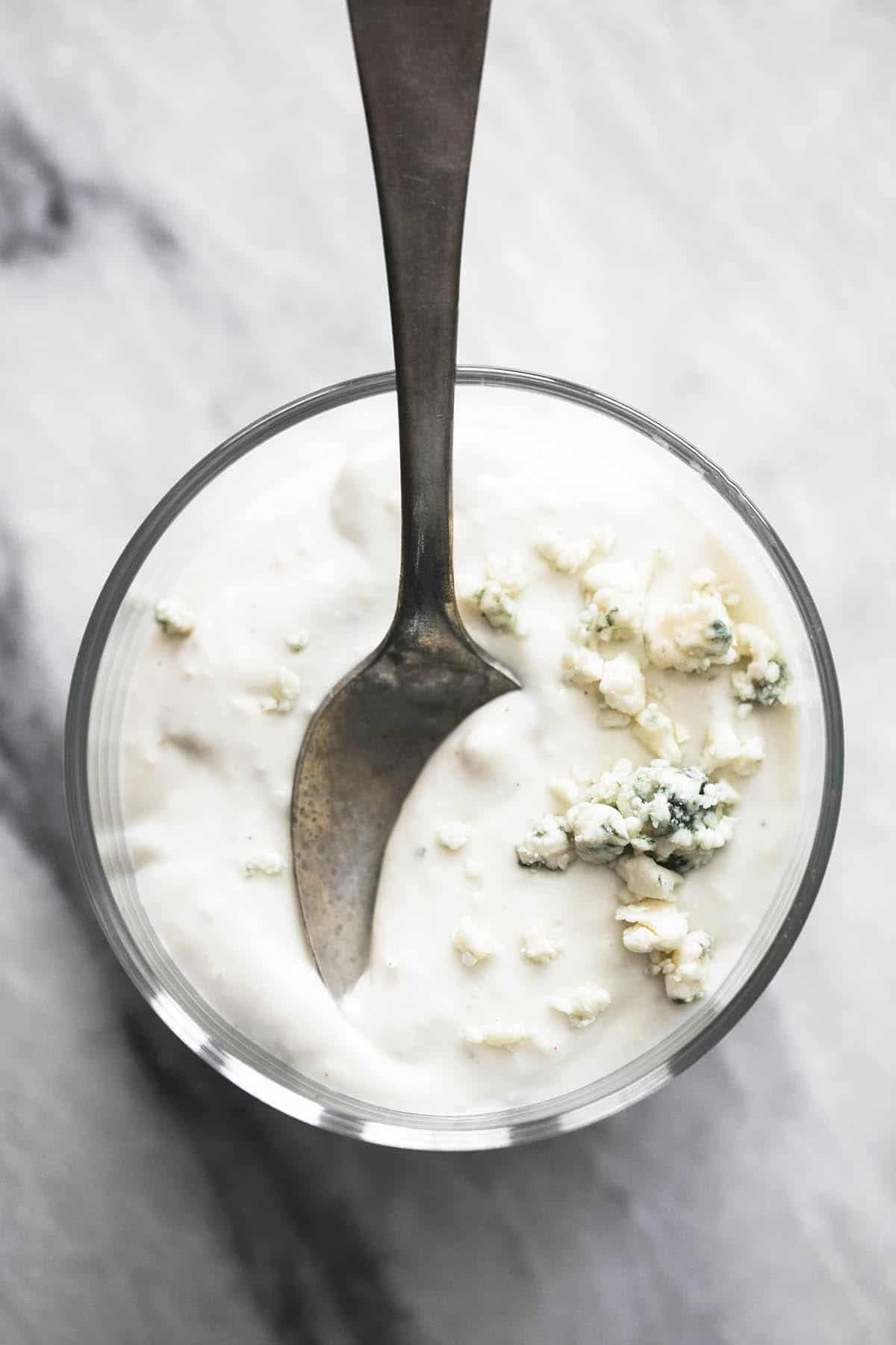 top view of blue cheese dressing in a glass with a spoon.
