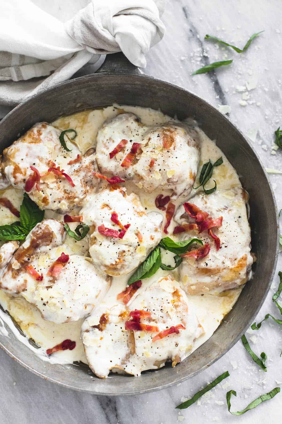 top view of creamy asiago bacon chicken in a cast iron.