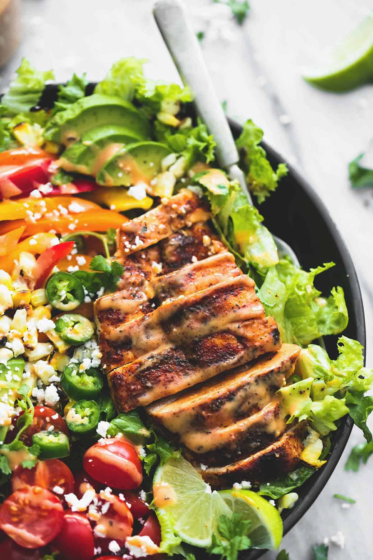 close up top view of fiesta lime chicken salad with chipotle dressing with a fork in a bowl.