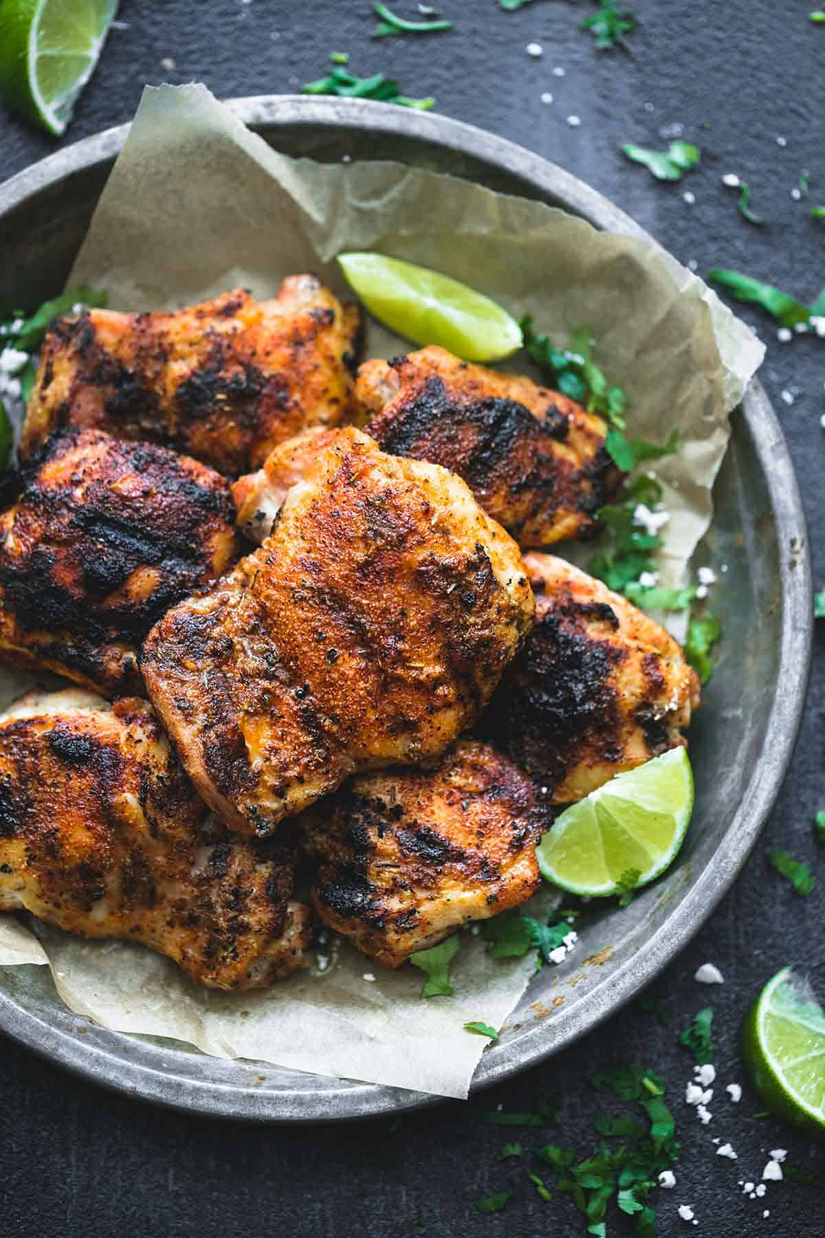 top view of grilled Cajun lime chicken in a metal tray with lime slices on the side.