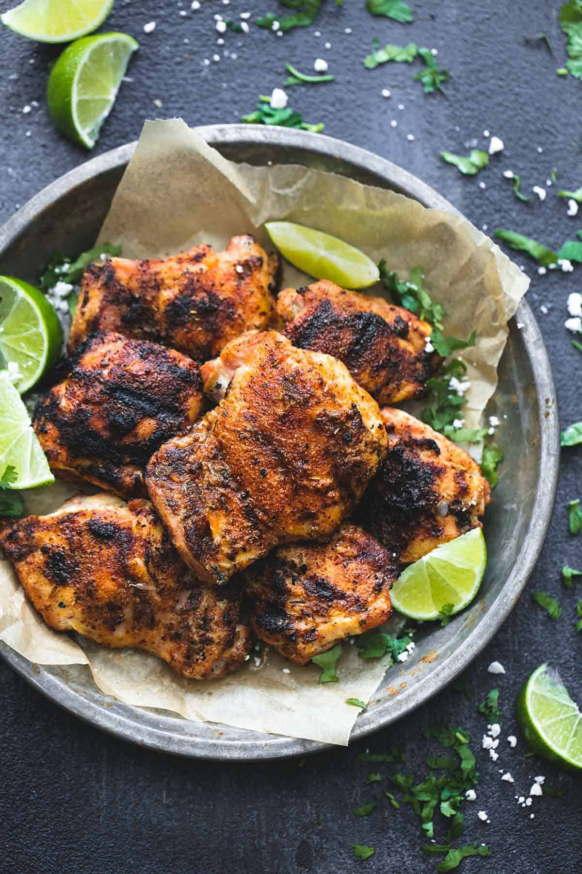 top view of grilled Cajun lime chicken with lime slices in a metal tray with more lime slices on the side.