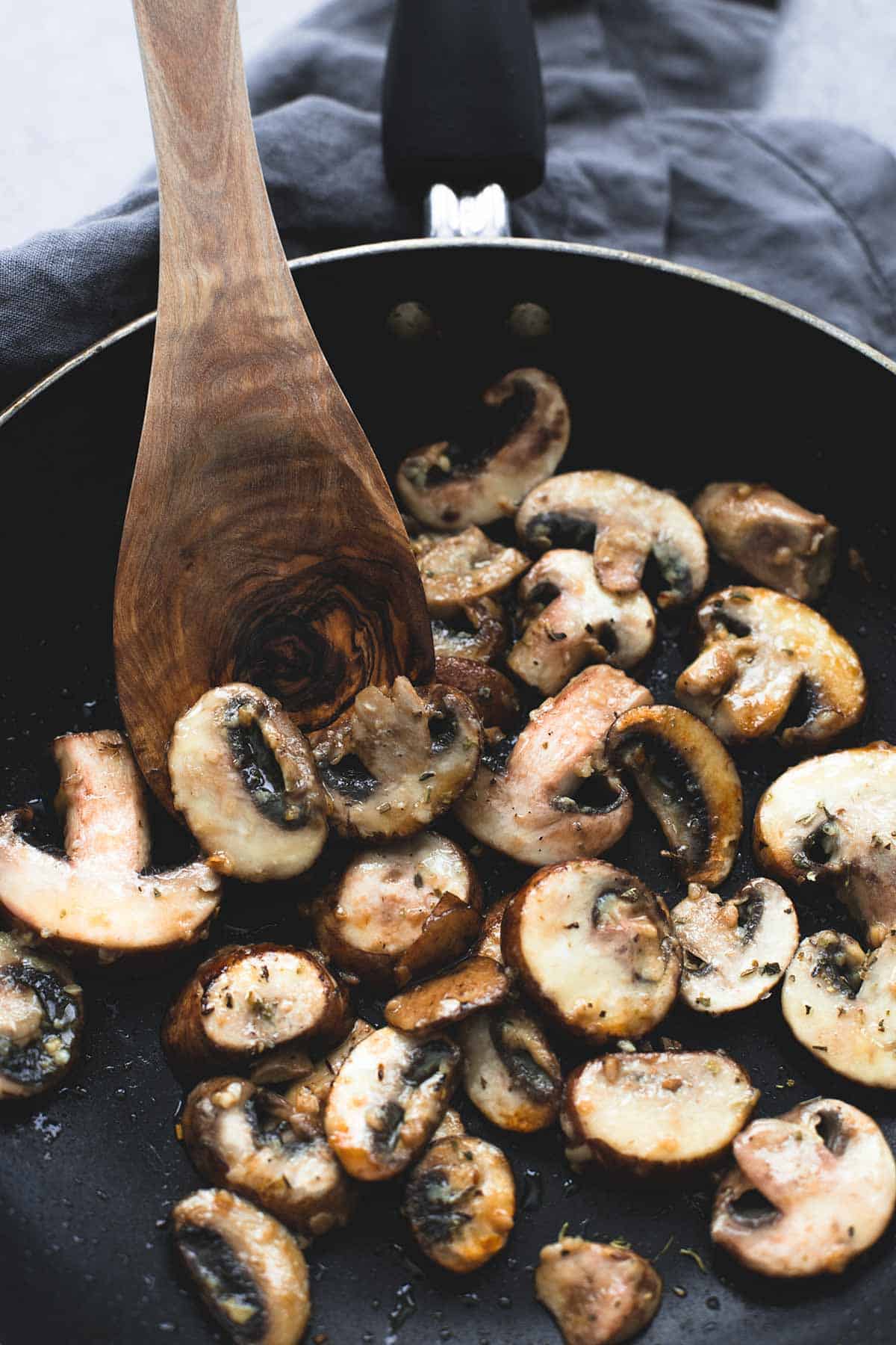 mushrooms and a wooden serving spoon in a pan.