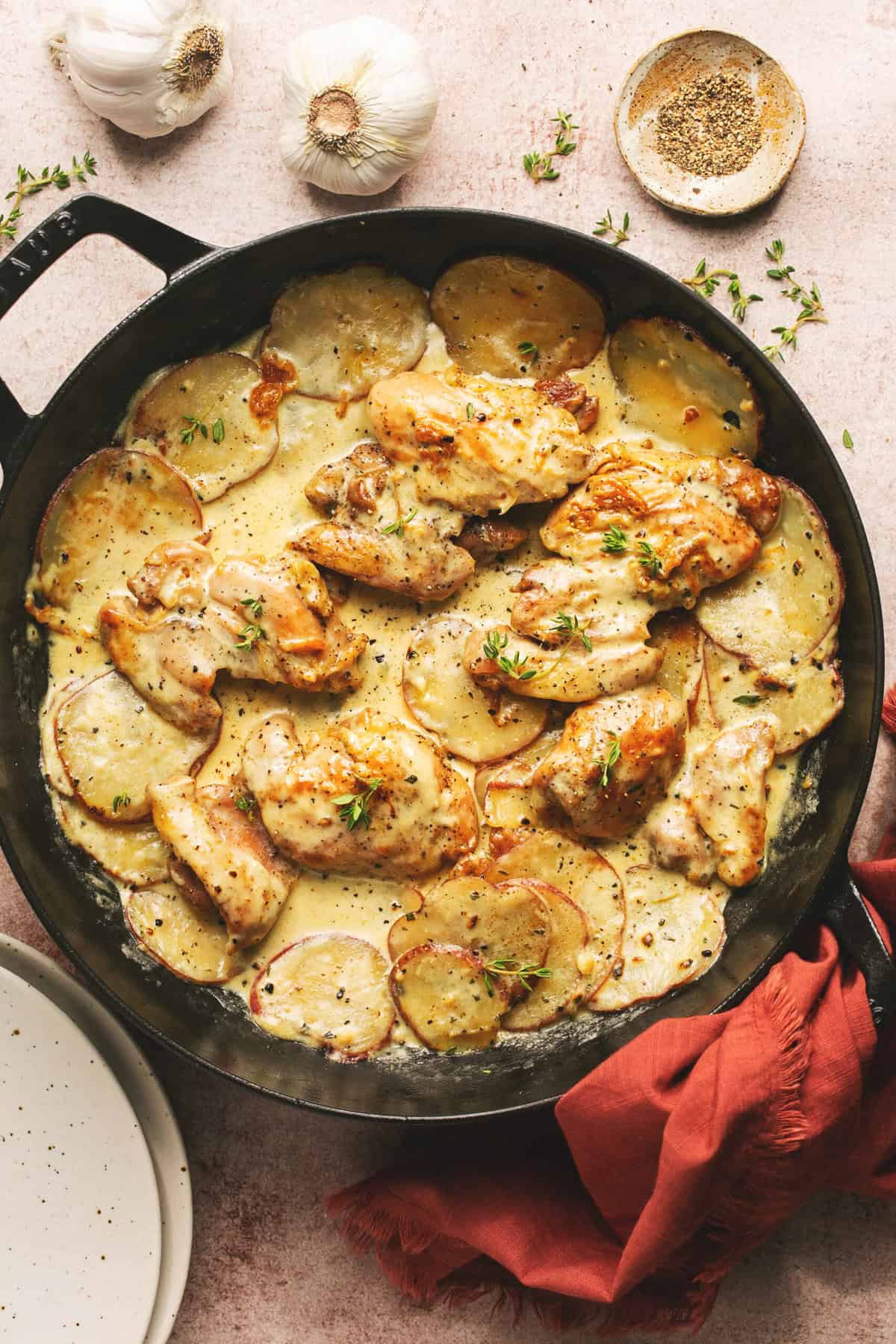 Overhead of oven baked creamy garlic chicken and potatoes in a cast iron skillet.