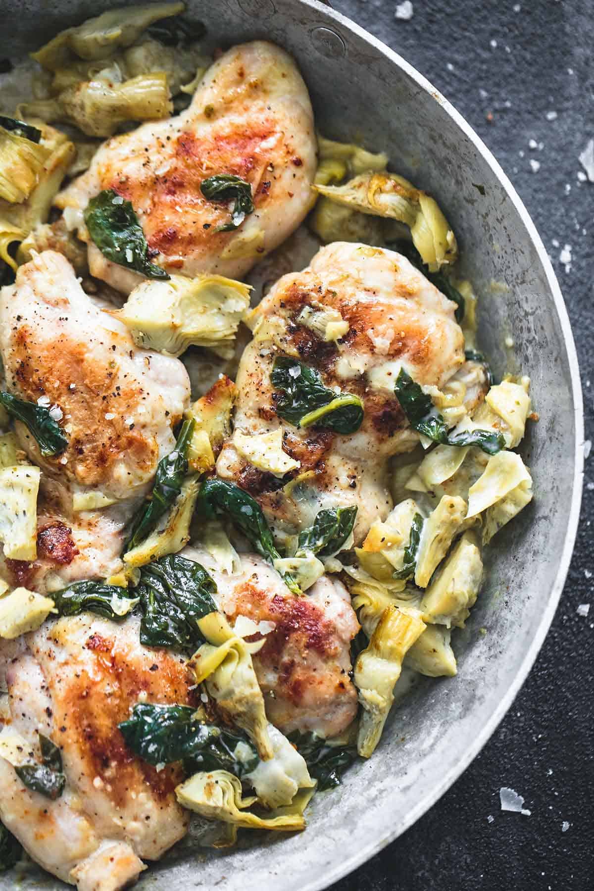 close up top view of spinach artichoke chicken in a skillet.