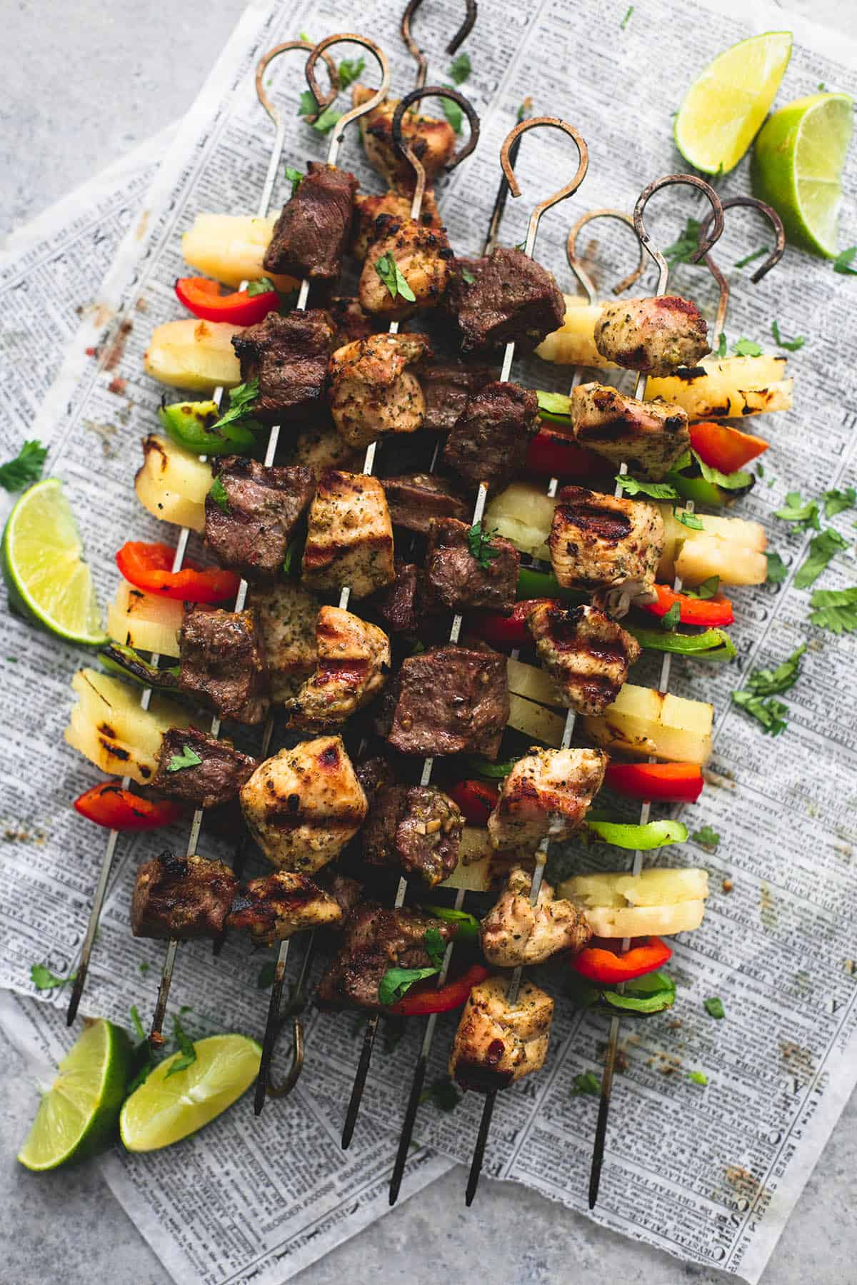 top view of Brazilian steak & chicken kabobs with lime slices on the side.