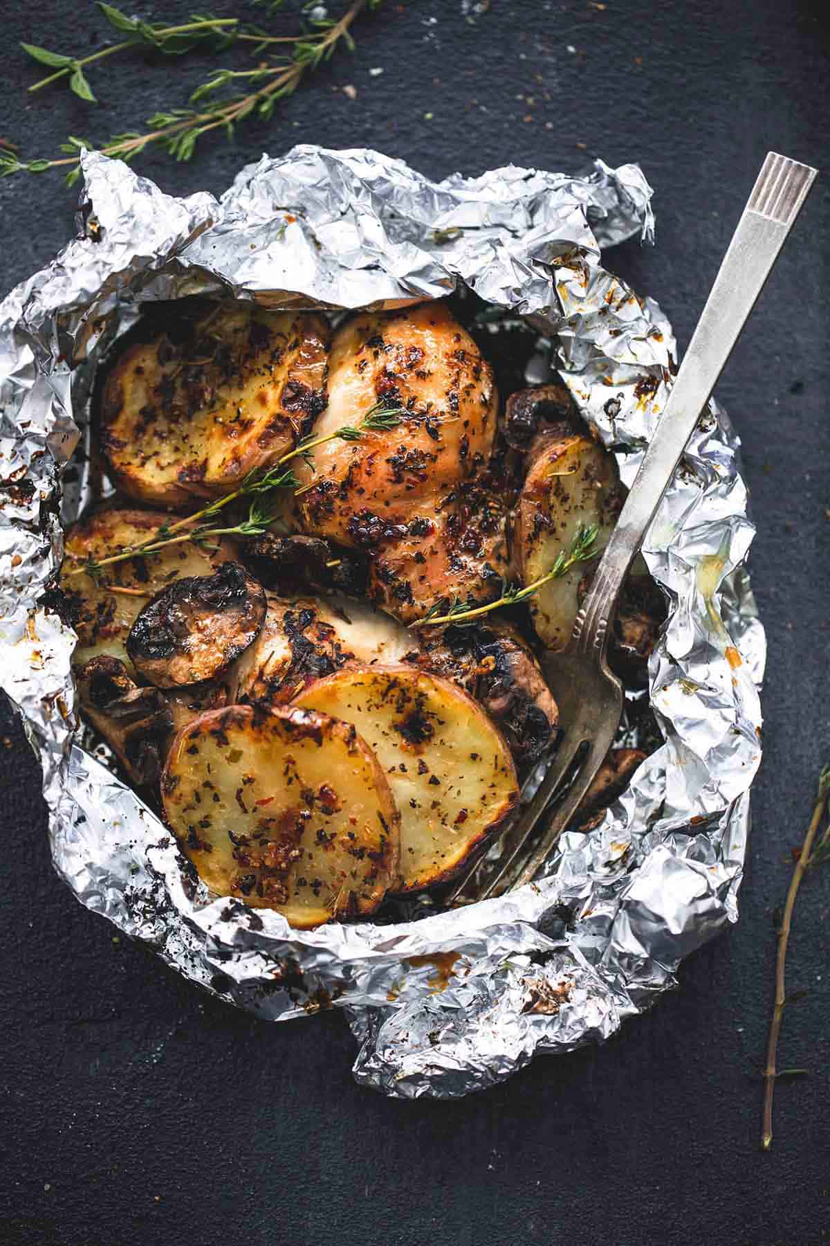 top view of a grilled herbed chicken & potato foil pack with a fork.