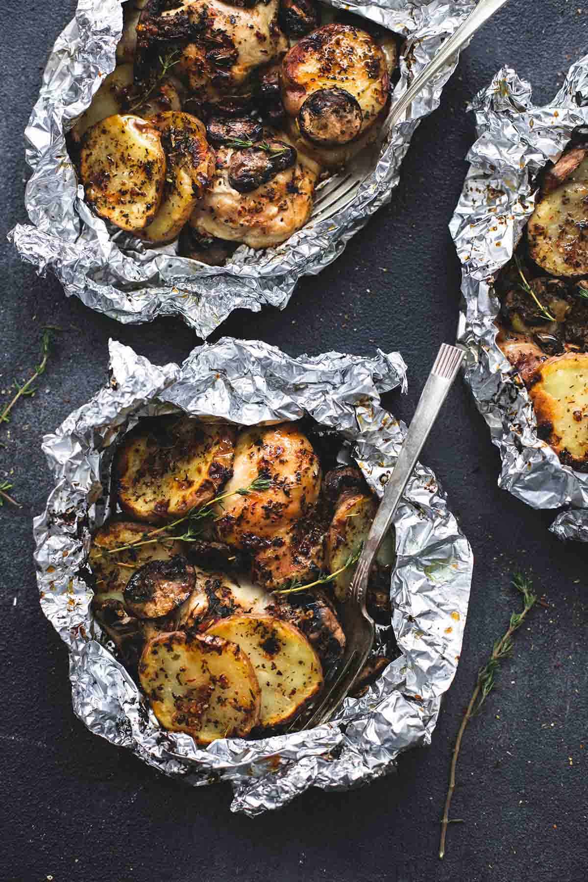 top view of grilled herbed chicken & potato foil packs with a fork in one.