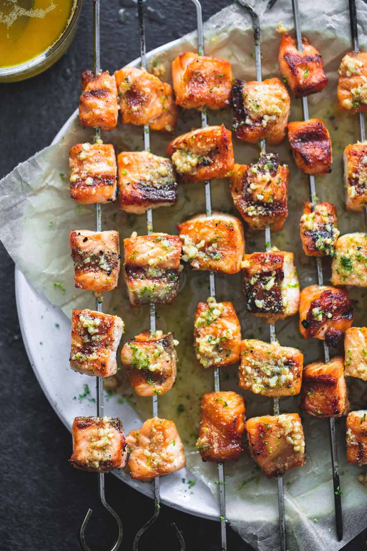 close up top view of grilled lime butter salmon skewers on a plate.