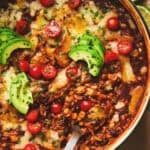 cheesy enchilada orzo pasta with serving spoon in cast iron pan