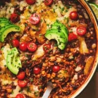 cheesy enchilada orzo pasta with serving spoon in cast iron pan.