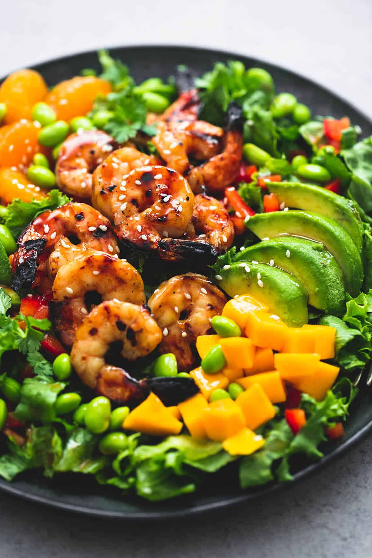 mango mandarin sesame shrimp salad on a plate.