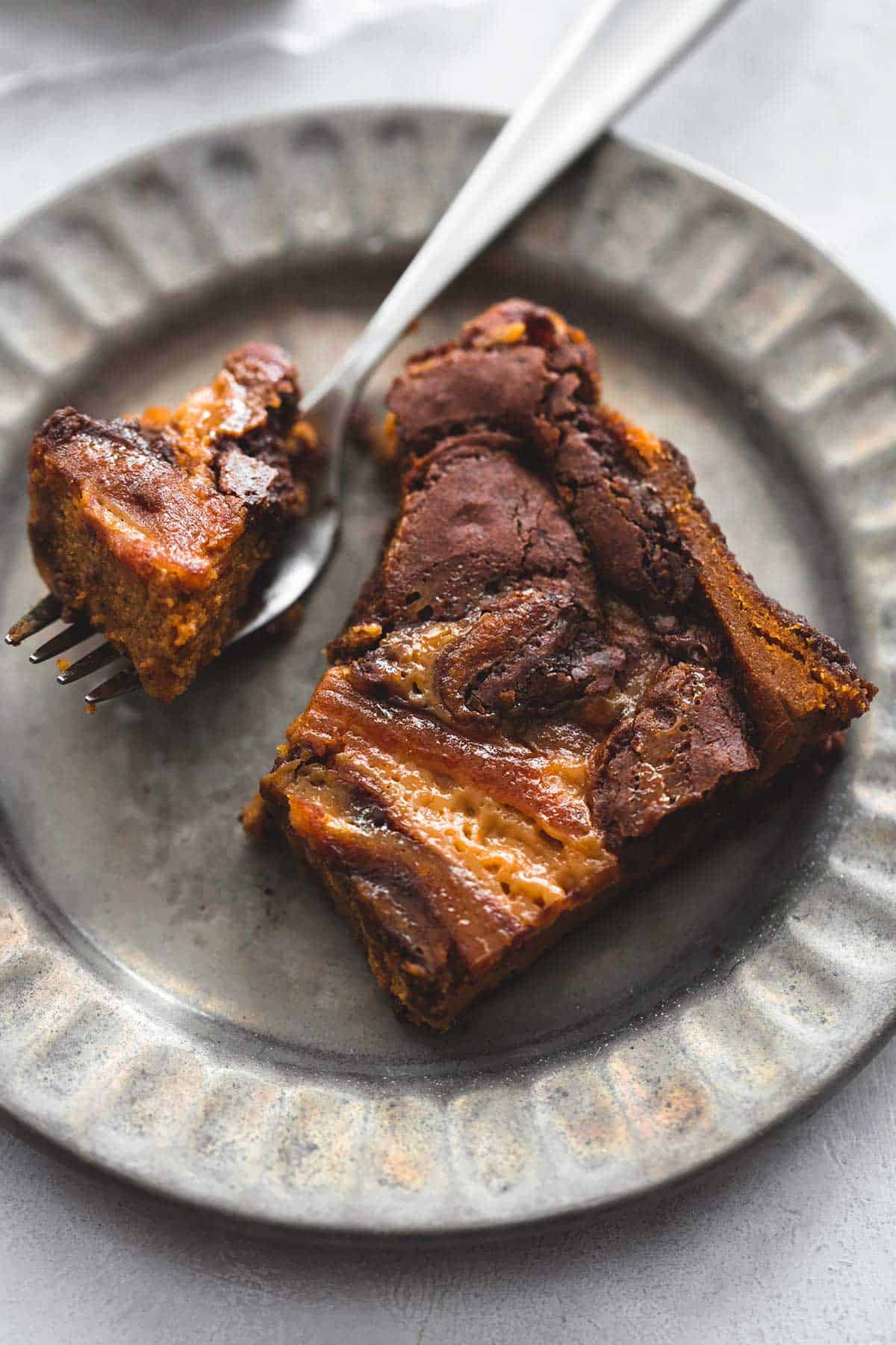 a gooey caramel pumpkin brownie with a bite of it on a fork on a plate.