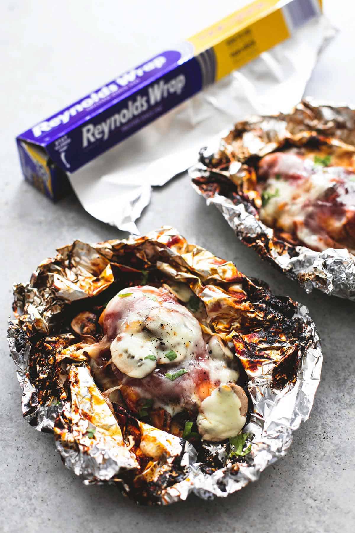 grilled smothered bbq chicken foil packs with a box of aluminum foil on the side.