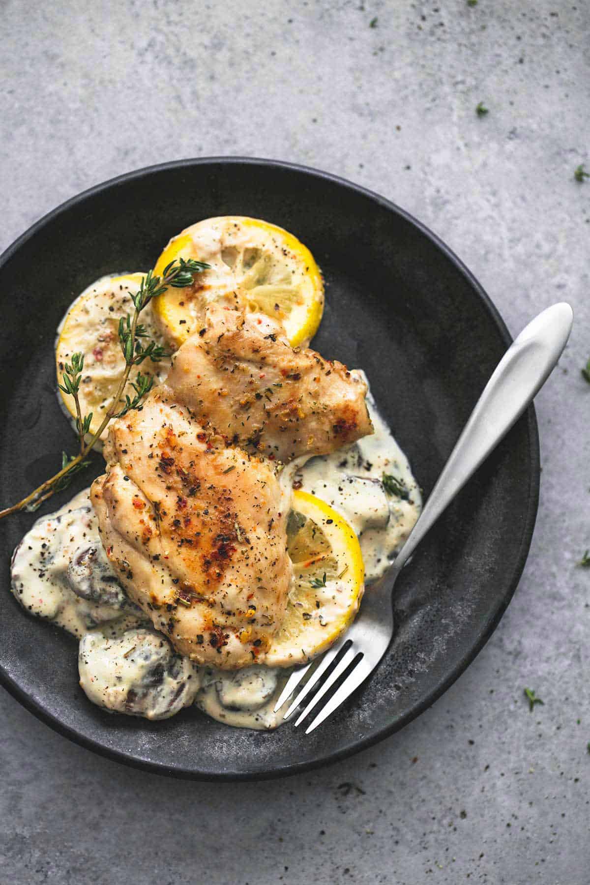 top view of creamy lemon thyme chicken with a fork on a plate.