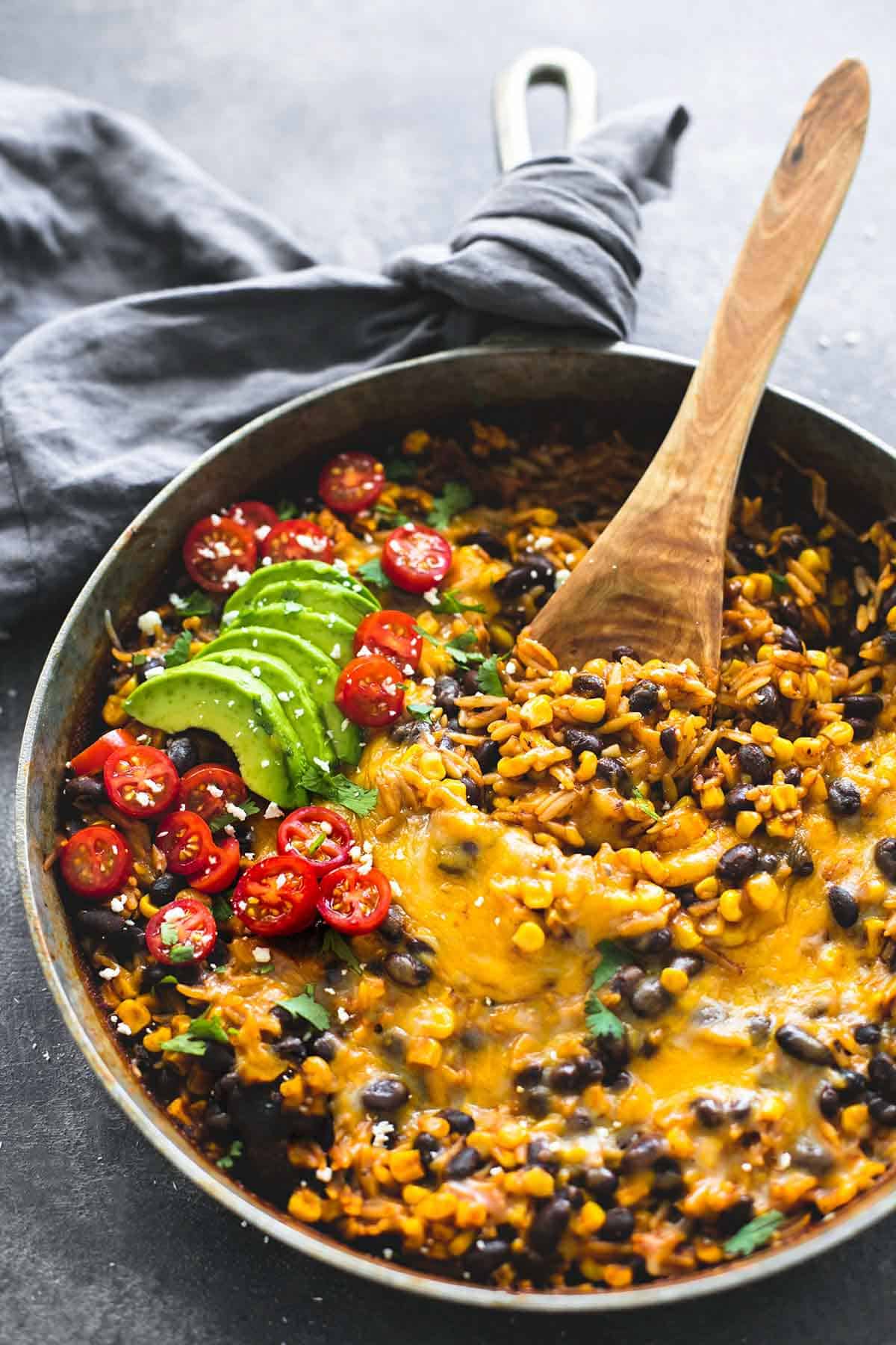 enchilada orzo with a wooden serving spoon in a pan.