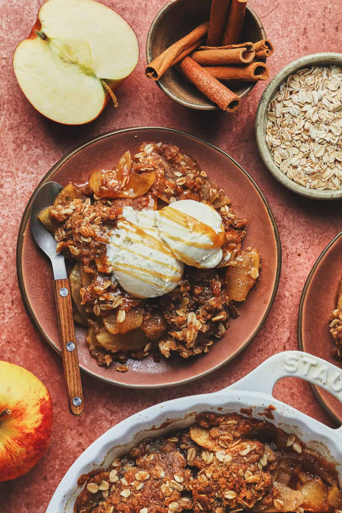 Overhead of a slice of apple crisp, with a scoop of vanilla ice cream and a fork on a plate.